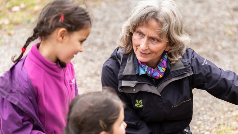 Volunteer crouched down speaking with children